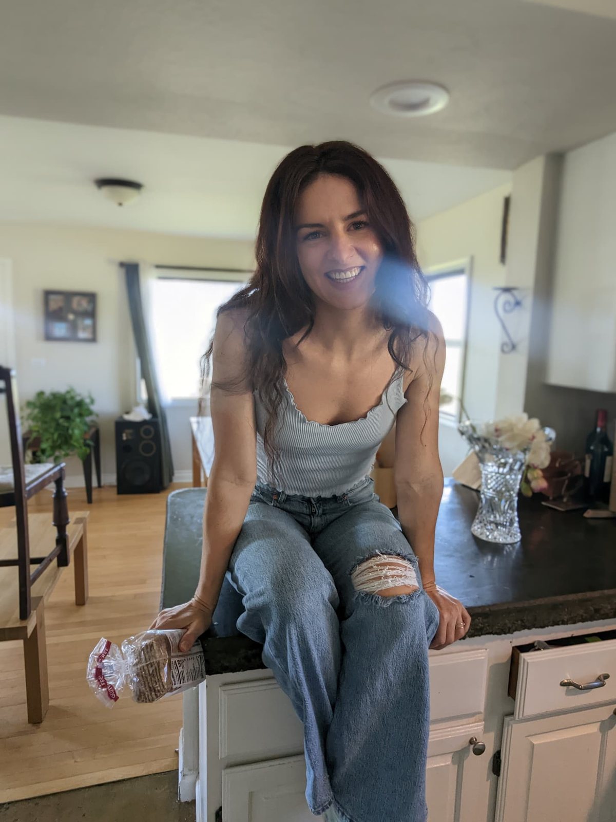 Ceylon sitting on her kitchen counter with a loaf of bread, smiling