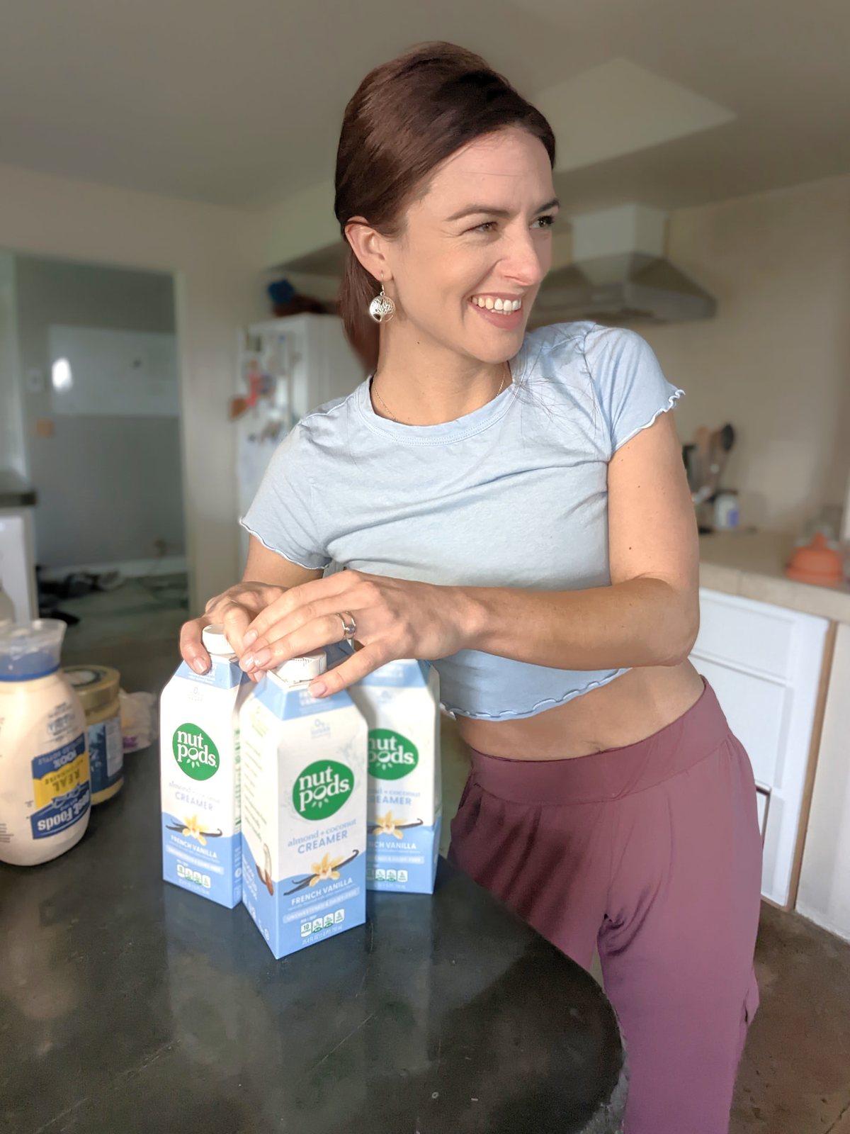 Ceylon in her kitchen with cartons of nut-pods creamer, smiling