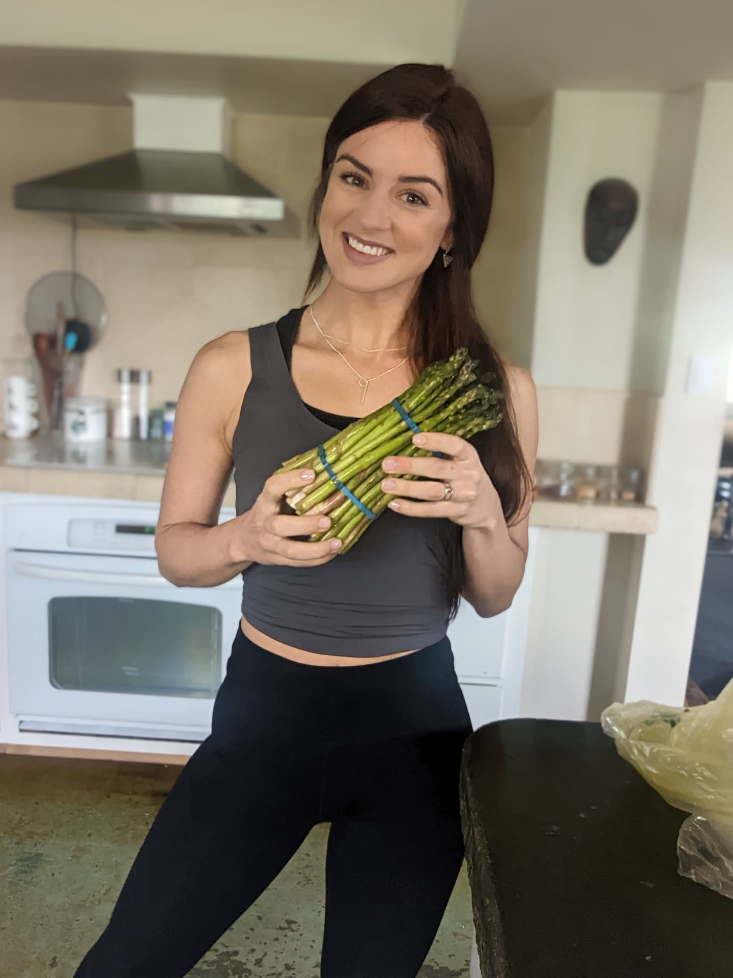 Ceylon holding a bunch of asparagus in her kitchen on a class slide