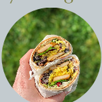 A hand holding two halves of a filled wrap against green grass